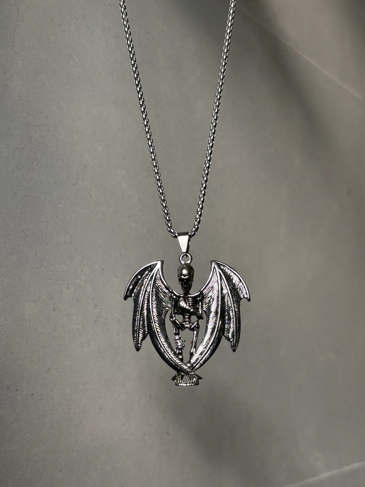 Anti-tarnish skeleton devil pendant necklace on a gray surface